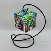 3-D CUBE ART #22 by Mary-Jo Lough, hand-painted 2.25” cube made from solid wood, featuring vibrant abstract art and layered details on a hanging stand.