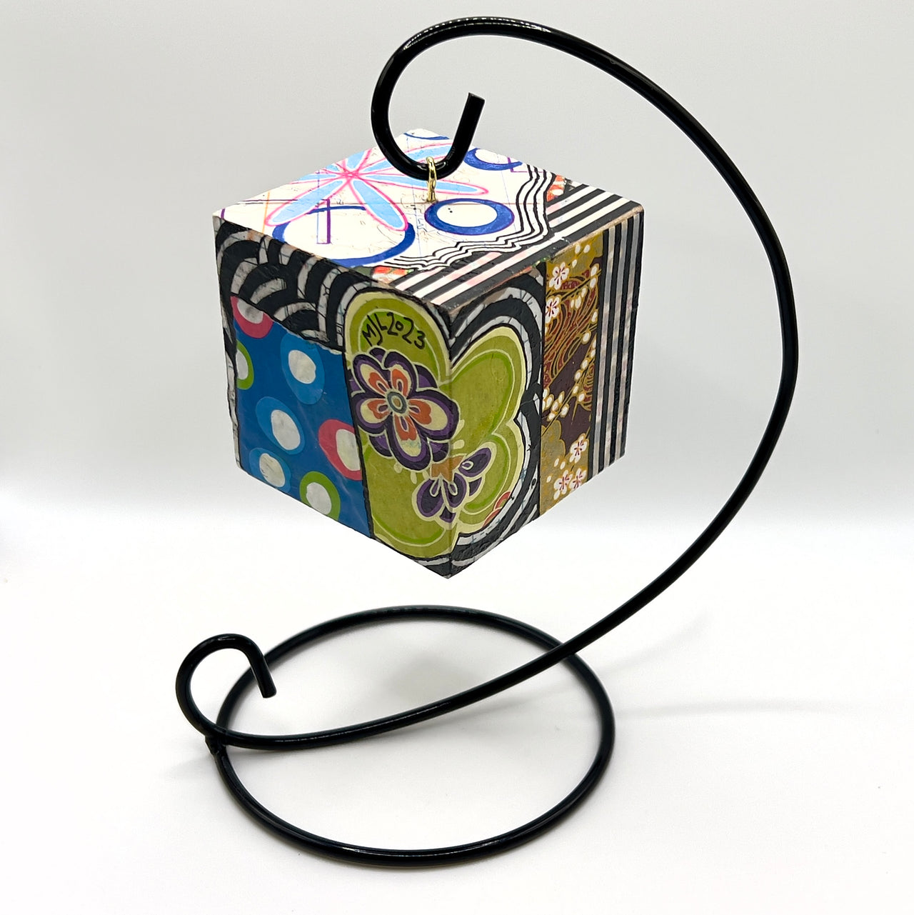 3-D CUBE ART #7 by Mary-Jo Lough, hand-painted 2.25” cube made from solid wood, featuring vibrant abstract art and layered details, on a hanging stand.